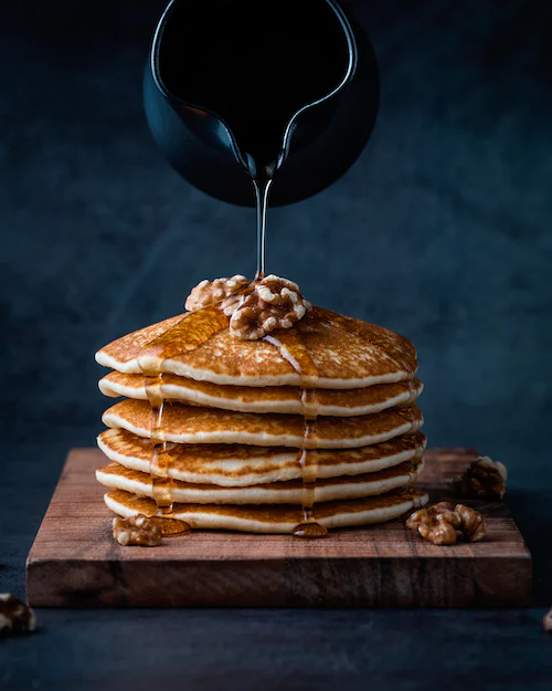 Stack of pancakes with nuts and honey.