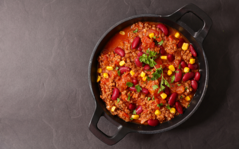 A pan of chili with corn and meat.