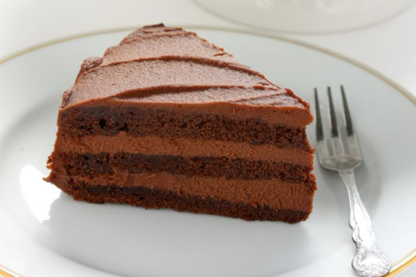 Chocolate cake on top of a silver platter, with a fork sitting to the right of it