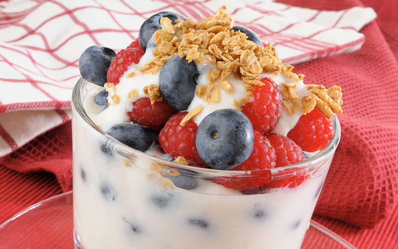 Delicious blueberries and raspberries on top of yogurt and oats in a small cup