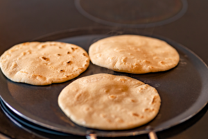 Three corn flour tortillas on a pan.