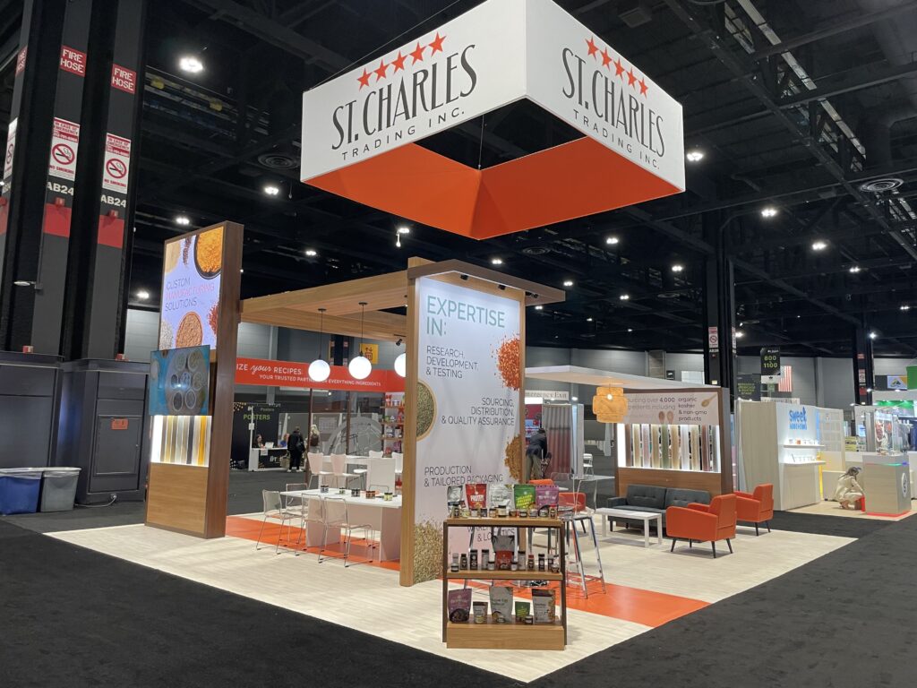 A photo of the St. Charles Trading booth at IFT. In front there is a table holding packaging ideas and shaker bottles full of spices.