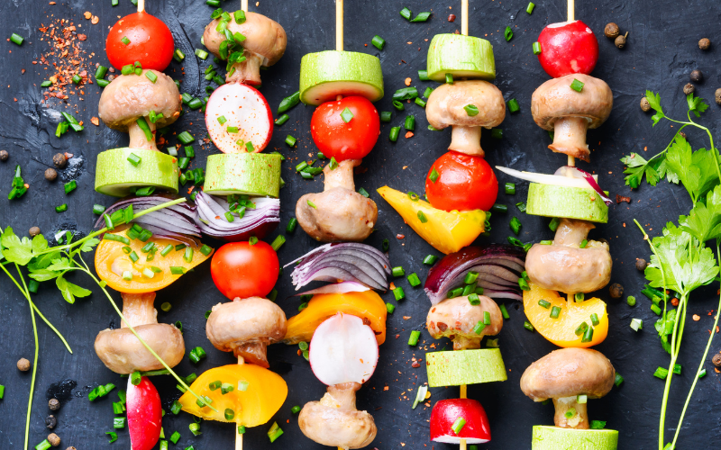 Grilled vegetables on a gray-ish charcoal background, skewered