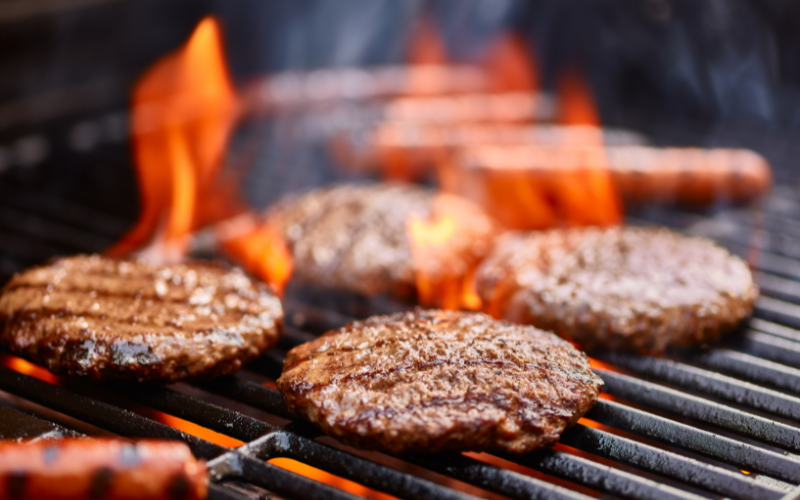 Four meat patties on a grill