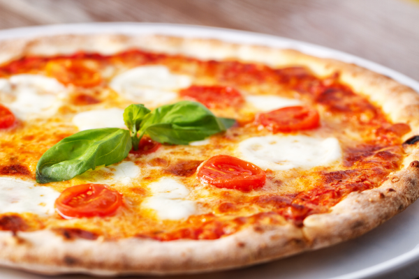 A photo of a circular Margherita pizza sitting on a white plate.