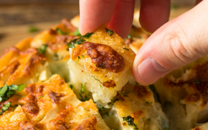 Someone pulling apart cheesy bread, for a halloween recipe