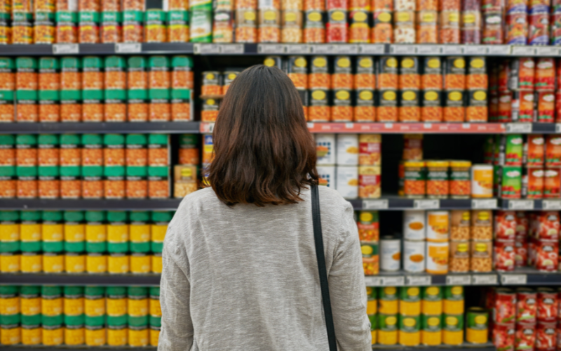 A woman stands in front of a grocery aisle that's packed with private label foods.