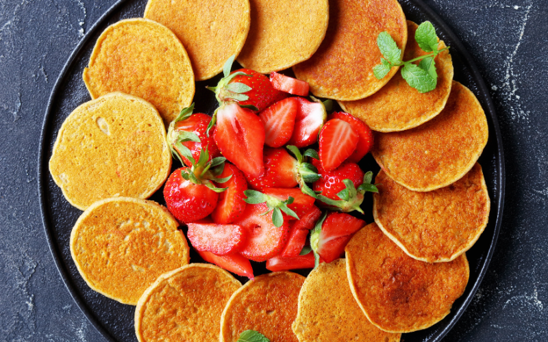 Pancakes made from Arrowroot powder, placed in a circular pattern over a circular tray, with strawberries adorned in the middle of the tray