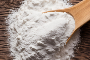 Arrowroot powder on a wooden spoon and splashed in the background countertop