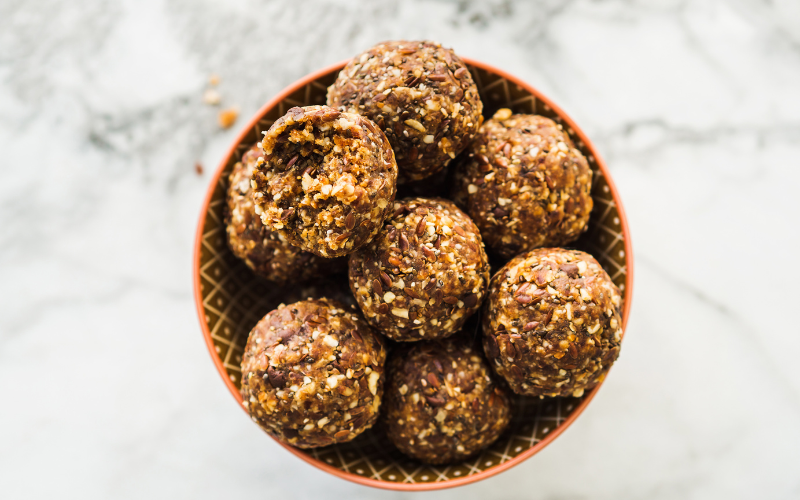 Peanut Butter Energy Balls on top of each other in a bowl, sitting on a white countertop in celebration of National Peanut Butter Day