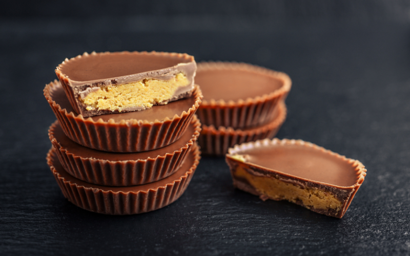 One half-eaten vegan peanut butter cup on top of a stack of four, with three beside it